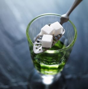 stock image of Absinthe in a glass with a proper absinthe "spoon" over top holding sugar cubes