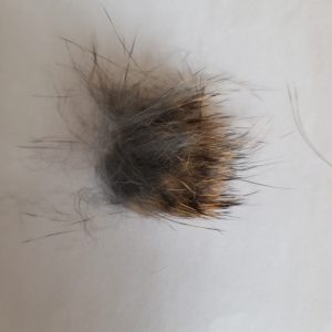 close up of fur on white background shows it's soft grey blending into beige then dark brown at the tips