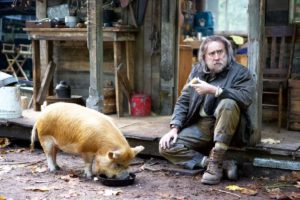 Nicolas Cage in the film "Pig" sitting next to his pig.