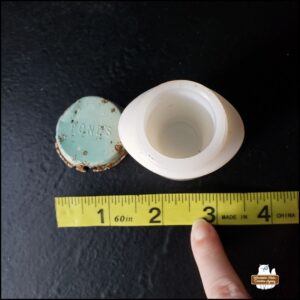 cleaned (top view) Pond's "artifact" jar and top of the light green (corroded) lid next to tape measure showing jar is approximately 2.25 inches and lid is 1.5 inches