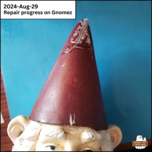 close up of the front of the tip of the gnome's conical hat during repairs showing cracks, super glue, and missing paint.