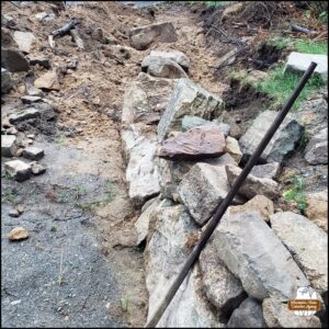 the excavation of the end of the upper parking lot with the beginning stages of building a new rock wall; all the dirt from the area that was grassy is uneven and treacherous.