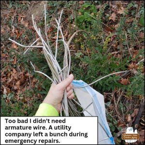 Amber's hand gripping a bunch of thick steel wire collected from the embankment of the road. caption: too bad I don't need armature wire. A utility company left a bunch during emergency repairs.