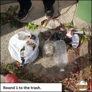 a white plastic shopping bag full of litter next to a clear plastic bag full of glass and next to loose trash like a car part, plastic bottles, and aluminum cans that could be recycled. caption: Round 1 to the trash.