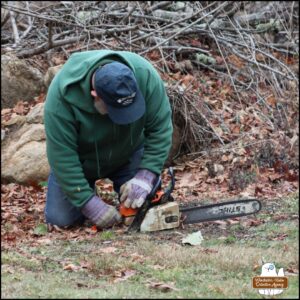 The Grumpy Old Man kneeling on the ground working the chainsaw.